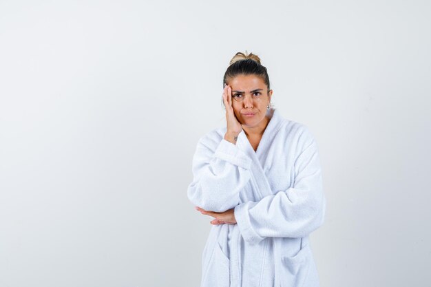 Young woman standing in thinking pose in bathrobe and looking thoughtful