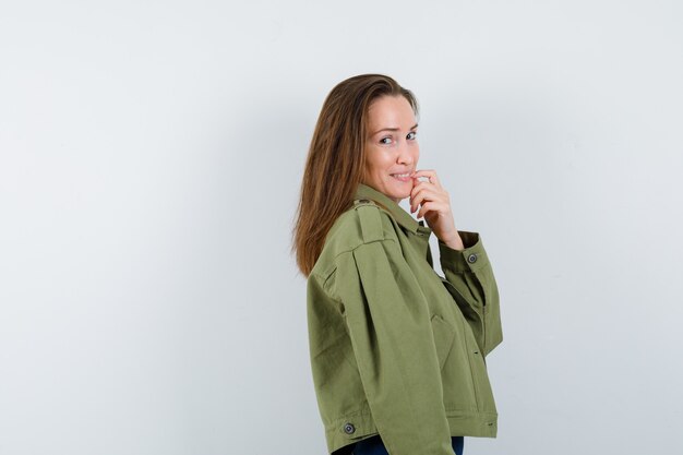 Young woman standing in thinking pose in jacket and looking graceful.
