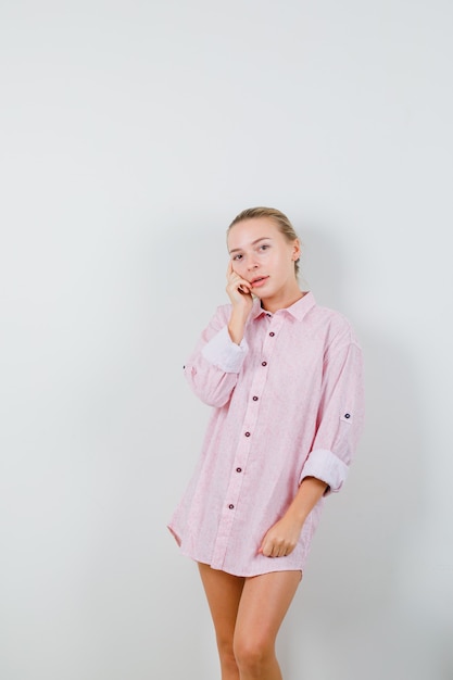 Young woman standing in thinking pose in pink shirt and looking cute