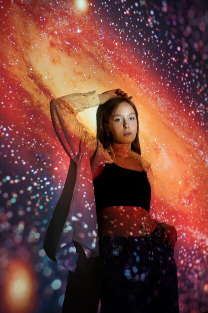 宇宙のテクスチャ投影に立っている若い女性