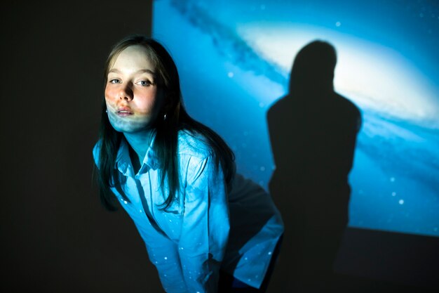 宇宙のテクスチャ投影に立っている若い女性