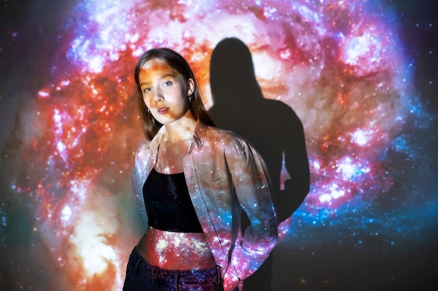 Молодая женщина, стоящая в проекции текстуры вселенной