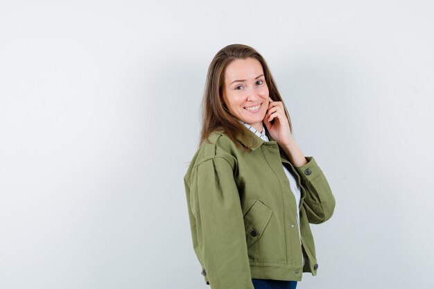 Young woman standing while posing in shirt and looking charming. front view.