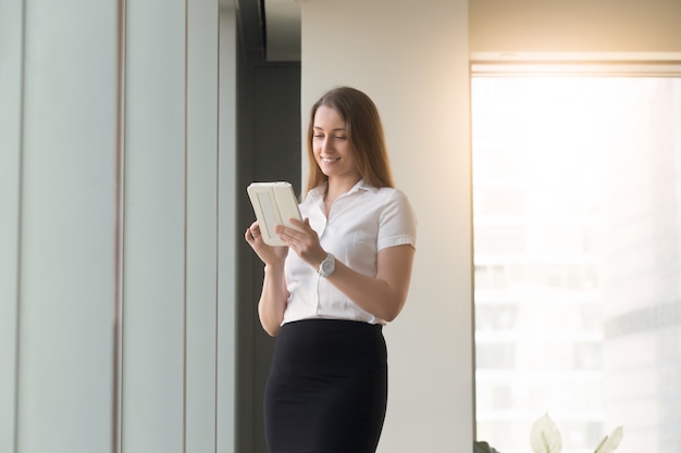 手でコンピューターのタブレットで立っている若い女性