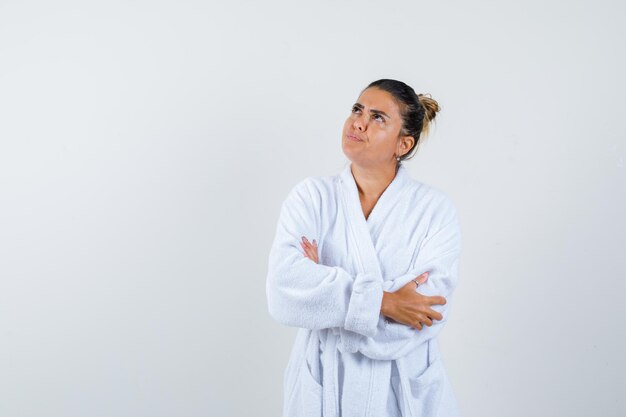 Young woman standing with crossed arms in bathrobe and looking confident