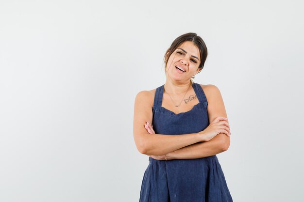 Young woman standing with crossed arms in dress and looking confident