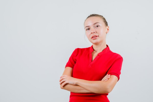 Young woman standing with crossed arms in red t-shirt and looking cute