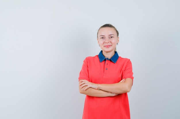 Free photo young woman standing with crossed arms in t-shirt and looking jolly