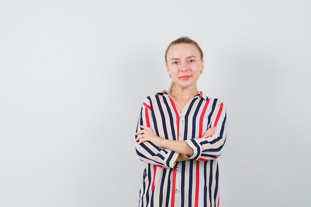 Free photo young woman standing with crossed hands and looking optimistic