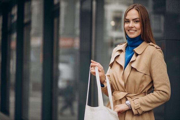 通りに彼女のバッグを持って立っている若い女性