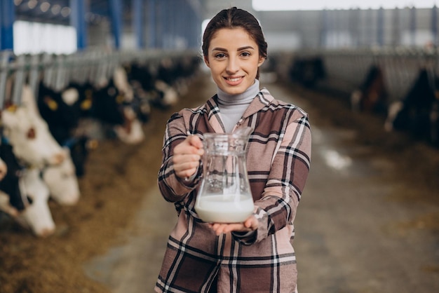 Young woman standing with milk jug at the cowshed