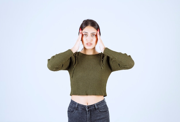 Young woman standing with painful headache on white background.