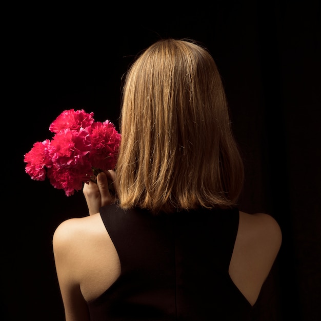 Foto gratuita giovane donna in piedi con fiori rosa