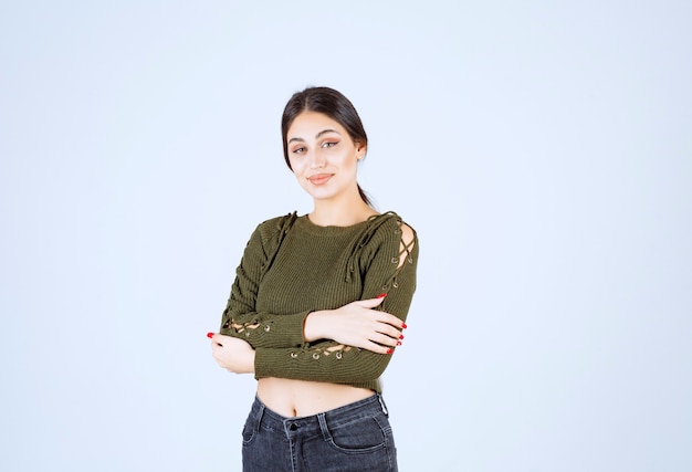 Young woman standing with smiling expression on white background.