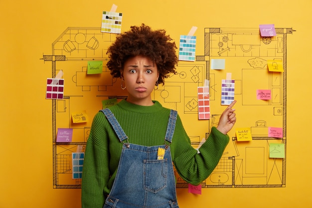 Young woman stands next to house design sketch ready for renovation