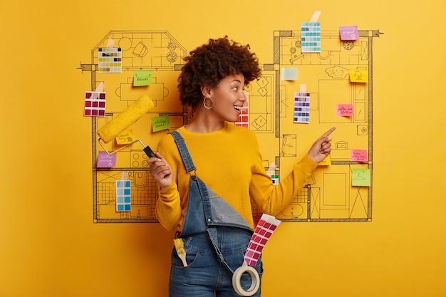 Free photo young woman stands next to house design sketch ready for renovation