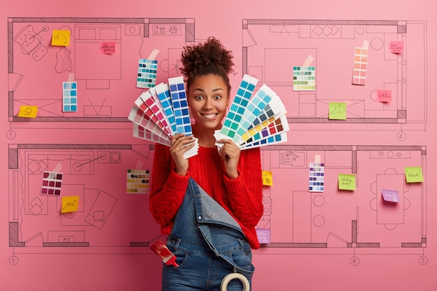 Young woman stands next to house design sketch ready for renovation