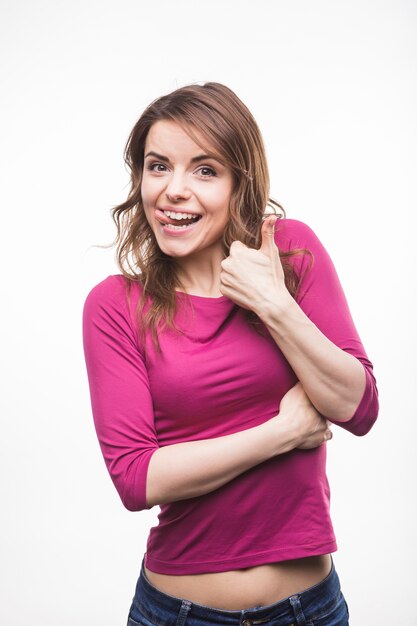 Young woman sticking her tongue out showing thumb up sign