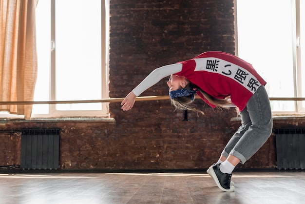 Free photo young woman stretching backward in the dance studio