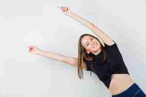 Free photo young woman stretching her arms aside in black blouse and looking happy.