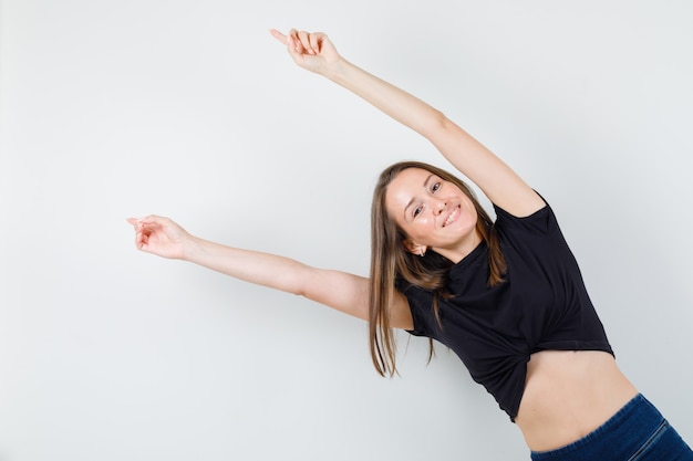 Young woman stretching her arms aside in black blouse and looking happy.