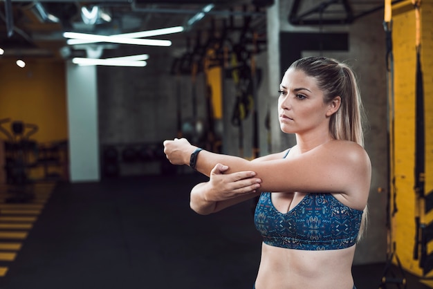 Young woman stretching her hand in fitness club