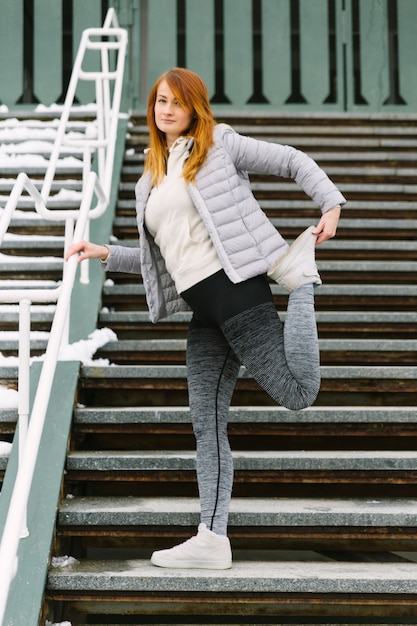 Young woman stretching her leg standing on bleachers