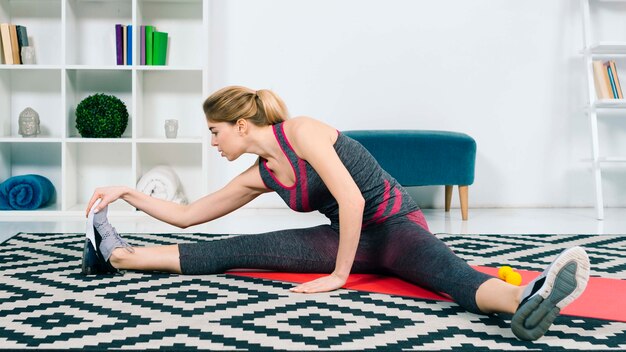 Young woman stretching her leg while sitting in the living room