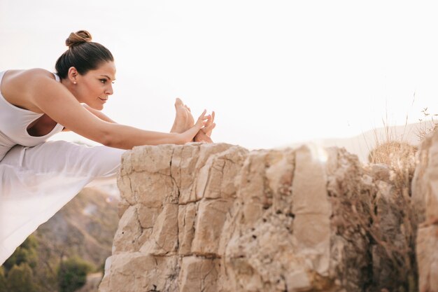 Young woman stretching leg outdoors