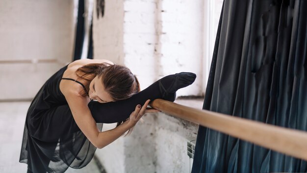 Young woman stretching near barre