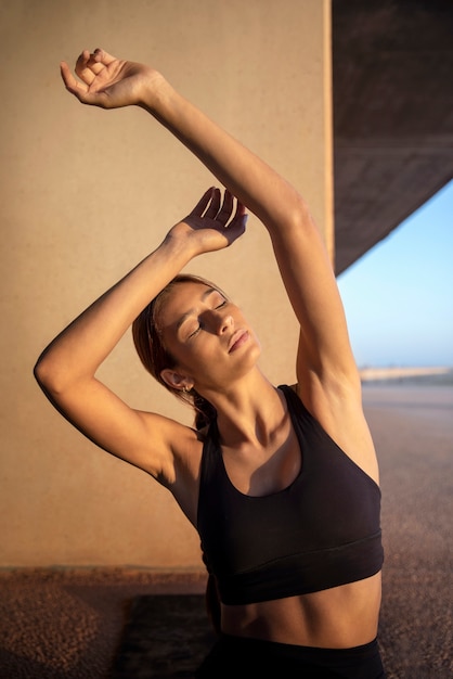 Foto gratuita giovane donna che si allunga e si prepara per l'esercizio all'aperto