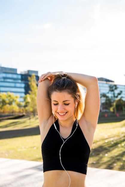 Free photo young woman stretching at the street