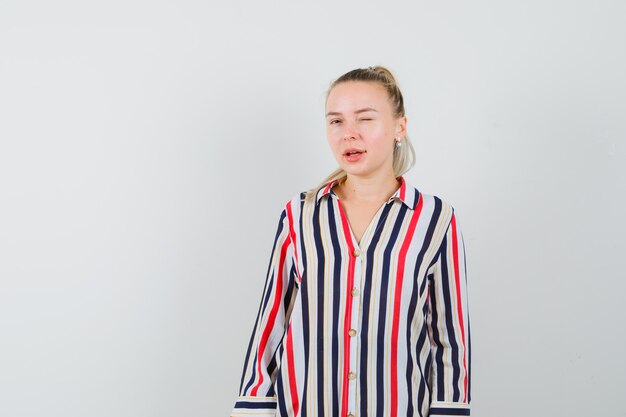 Free photo young woman in striped blouse blinking  and looking beautiful