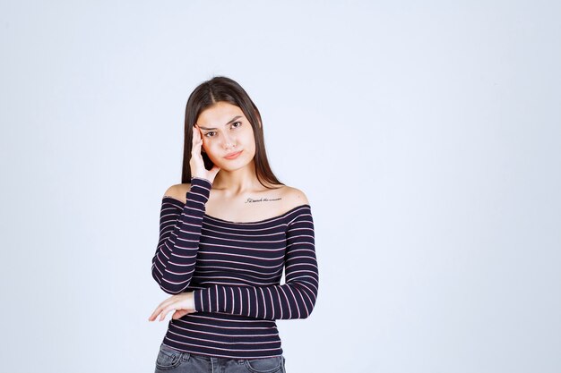 Young woman in striped shirt holding her head because of headache