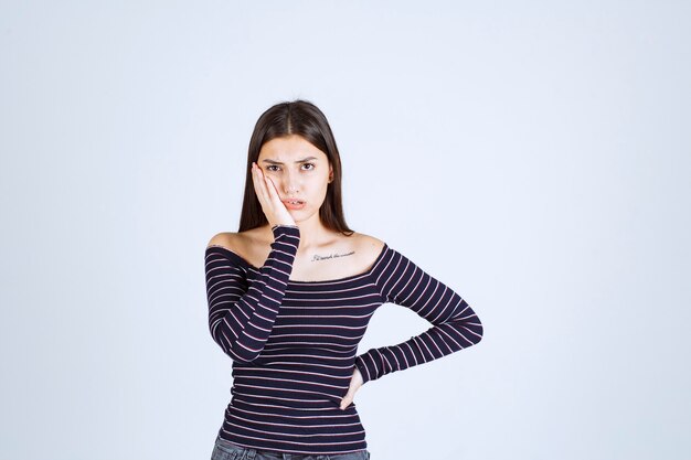 Young woman in striped shirt holding her head because of headache