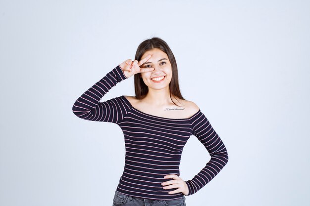 Young woman in striped shirt sending peace sign