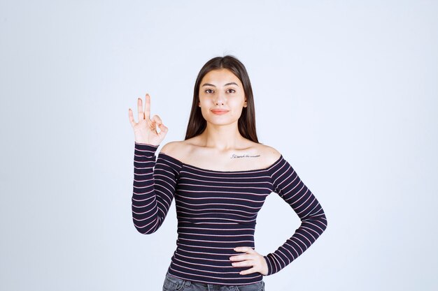 Young woman in striped shirt showing enjoyment hand sign