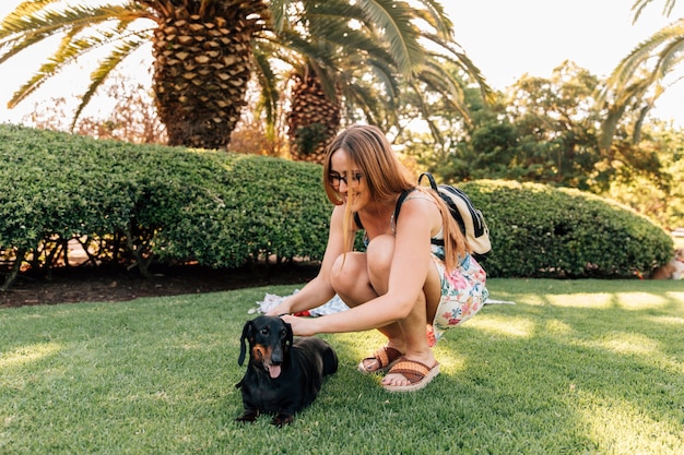 Молодая женщина, поглаживая ее собаку в парке