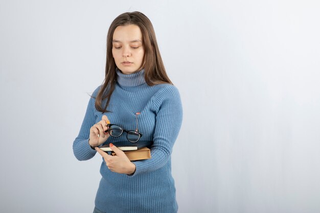 本と眼鏡を保持している若い女性の学生。