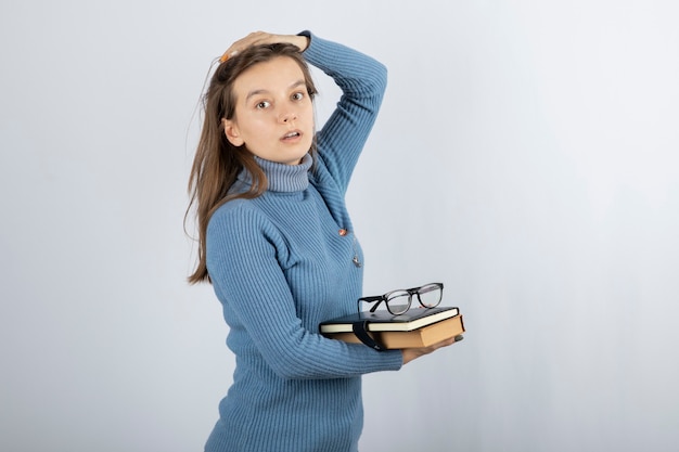 Free photo young woman student holding books and glasses.