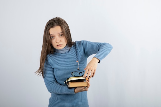 young woman student holding books and glasses.