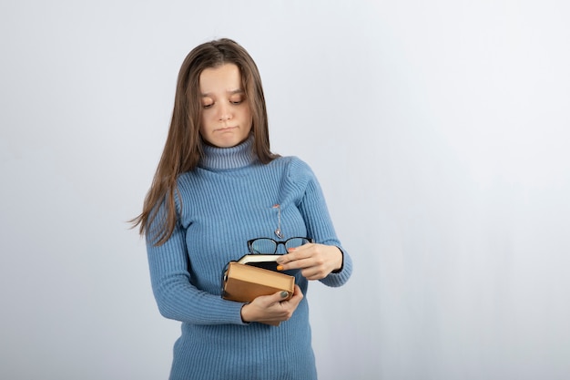 young woman student holding books and glasses.