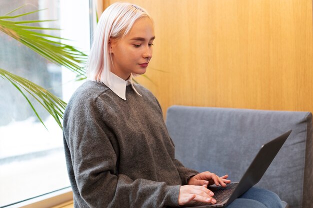 Молодая женщина учится в библиотеке, используя ноутбук