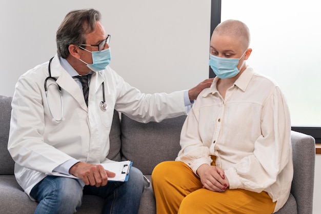 Young woman suffering of breast cancer talking with her doctor