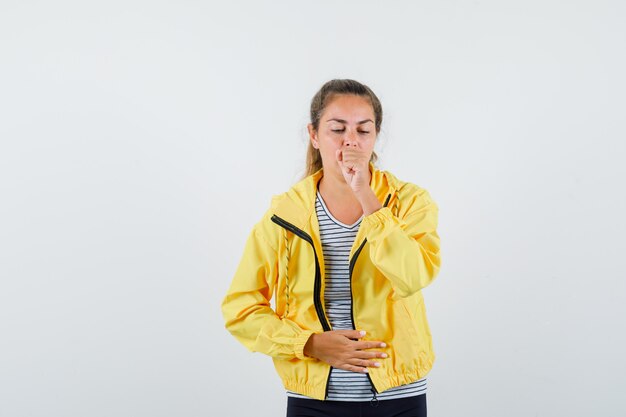 Young woman suffering from cough in t-shirt, jacket and looking ill. front view.