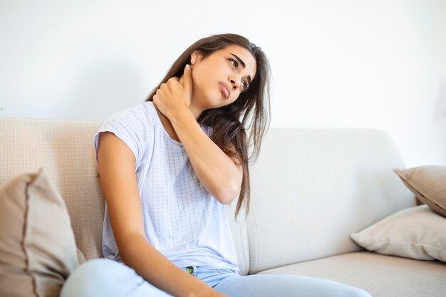 Young woman suffering from neckpain People healthcare and problem concept unhappy woman suffering from neckpain at home Neckpain caused by not taking care of health