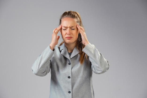 Young woman suffers from pain feels sick ill and weakness isolted on  wall