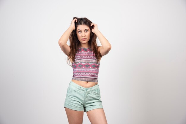 Young woman in summer clothes posing over a gray wall.