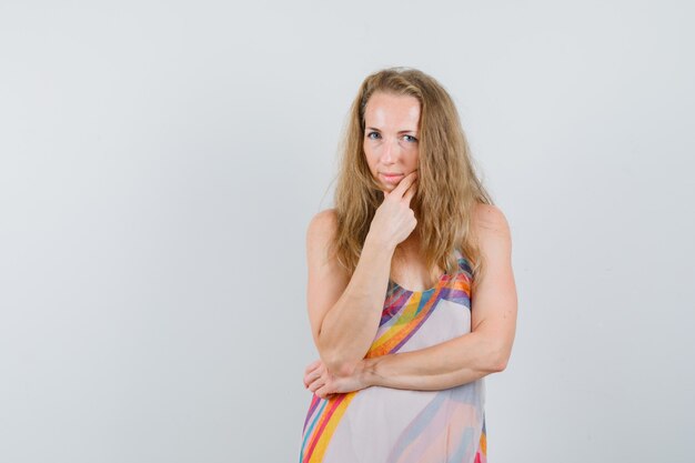 Young woman in summer dress holding her chin and looking sensible 