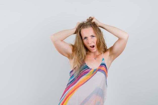 Free photo young woman in summer dress posing with hands on head and looking crazy